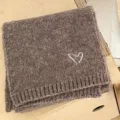 Brown knitted winter scarf detail featuring a cute white heart embroidery pattern. - Coffee Scarf