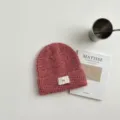 Primer plano del gorro de punto rosa acogedor con textura fina y etiqueta pequeña tejida. - Sombrero Rosa
