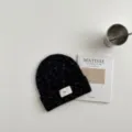 Vista detallada del gorro de punto negro para niños con textura suave sobre la mesa. - Gorro negro