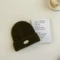 Gros plan détail du bonnet en tricot vert foncé pour enfants avec écusson, texture. - S / Vert Foncé