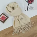 Detailansicht des warmen, beigefarbenen Kaschmirimitat-Schals mit Fransen und stilvollem Label. - 68x200cm / Beige