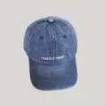 Nahaufnahme Detail der blauen Jeans Baseballkappe mit weißer HUSTLE HARD Stickerei vorne. - M (56-58cm Verstellbar) / HUSTLE Buchstabe Gestickter Stil / Dunkelblau