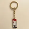 Detail shot of the travel themed airplane ticket metal keychain in stylish gold finish. - Red Ticket