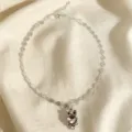 Gros plan d'un délicat collier avec pendentif hibou argenté et cristaux étincelants. - Rose