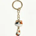 Cute calico cat keychain with dangling tail design, gold plated metal finish and enamel details. - Waving Tail Cat Keychain / Calico