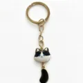 Cute black and white cat metal keychain with gold ring and dangling tail charm accessory. - Black and White