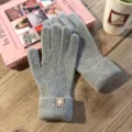 Nahaufnahme von kuscheligen Strick-Winterhandschuhen in Grau mit stilvollem Aufnäher. - Einheitsgröße / Hellgrau