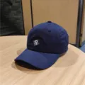 Detailed shot of a navy blue baseball cap with white R embroidery on a wooden table. - M (56-58cm) / Navy Blue