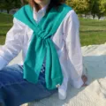 Detailed shot of a cozy teal knitted cross scarf shawl, elegant neck warmer worn outdoors. - One Size / Lake Blue