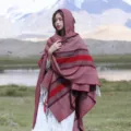 Detailed view of the autumn winter knit hooded poncho shawl with tassels in ethnic red stripes. - Classic Stripe Hooded Poncho, Wine Red