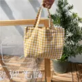 Detalle de un pequeño bolso de mano a cuadros amarillos y blancos con fondo de madera - Amarillo