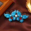 Nahaufnahme einer retro blauen Schmetterlings-Haarklammer mit Perlen und roten Kristallen. - Emaille Doppel-Schmetterling-Clip mit Roter Perle