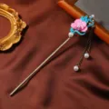 Primo piano di un bastoncino per capelli vintage in stile cinese con fiore smaltato e nappa. - Stile Dea dei Fiori 12
