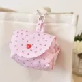 Close-up detail of the pink striped cherry print mini storage pouch with heart button and chain. - Pink Cherry
