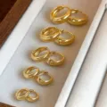 Nahaufnahme eines abgestuften Sets vergoldeter Creolen, ordentlich im Schmuckfach platziert. - 10mm / Gold