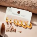 Detailansicht eines minimalistischen goldenen Edelstahl-Ohrring-Sets auf weißem Display. - Runder Stil (ZE0769)
