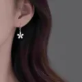 Gros plan des boucles d'oreilles pendantes fleurs en argent, style anneau élégant porté. - Style Boucles d'Oreilles Pendentif Fleur Française (MY37236)