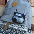 Close-up detail of grey polka dot canvas backpack featuring 3D husky dog badge and geometric pattern. - Scornful Husky