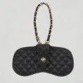 Detailed view of black quilted leather glasses case featuring a luxury gold chain. - Black