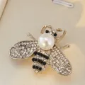 Detailed close-up of a sparkling rhinestone bee brooch featuring a faux pearl head and crystals. - Silver Bottom White