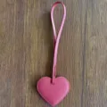 Primer plano detallado del colgante de bolso de cuero PU rosa en forma de corazón en madera. - Rosa rojo