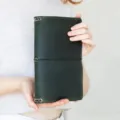Dark green PU leather A5 notebook cover with elastic band closure and metal eyelet details. - Green