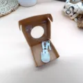 Close-up detail of mini household scissors with white storage pouch in open craft box. - White