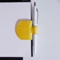 Detail shot of the yellow leather magnetic pen clip and bookmark holding a white pen securely. - Yellow