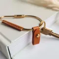 Close-up detail of brass metal loop keyring with brown PU leather wrap and snap button. - Brown