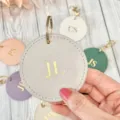 Close up of round pu leather keychain with gold foil letter engraving, modern personalized keyring detail. - Gray