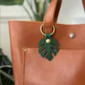Close-up detail of green monstera leaf leather bag charm keychain pendant accessory. - Leaf Spring Ring Style