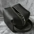 Black leather cosmetic bag travel makeup storage pouch with zipper and handle detail. - Black
