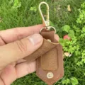 Close-up detail shot of brown PU leather mini photo frame keychain with gold clasp. - Brown