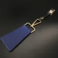 Detailopname van de blauwe PU-lederen golfhoedclip met goudkleurige metalen hardware en sluiting. - Blauw
