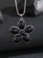 Primo piano dettagliato di una collana d'argento con ciondolo a fiore nero a cinque petali. - Nero