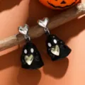 Nüchterne Detailaufnahme von Halloween schwarzem Geist Ohrringen mit goldenem Herz auf Ast. - Schwarzer Geist Stil / Schwarz