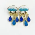 Close-up of cute cloud and blue raindrop tassel earrings with gold trim and enamel detail. - Dark Blue