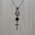 Detailed close-up of retro silver cross heart pendant necklace with black crystal bead. - Silver