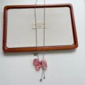 Primo piano di una collana lunga con ciondolo a forma di cagnolino in acrilico rosa originale. - Collana Cucciolo Rosa (XL4776A)