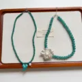 Vista dettagliata di collana di perle verdi vintage con fiore d'argento e cuore blu, piatto. - Stile Cuore Fiore Blu (XL4957)