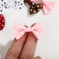 Close-up of a mini pink polka dot grosgrain ribbon bow shown on fingers for scale - Polka Dot Bow / Pink