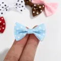 Close-up of a mini light blue polka dot grosgrain ribbon bow held for scale - Polka Dot Bow / Light Blue