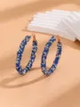 Close-up of dazzling blue and silver rhinestone large hoop earrings, elegant jewelry detail shot. - Blue & White