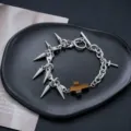 Gros plan d'un bracelet de chaîne à pointes en métal punk avec pendentif croix marron. - Bracelet Punk à Rivets Croisés (S0031-A)