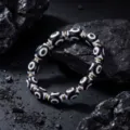 Detail shot of Tibetan black and white Dzi bead bracelet with metal spacers on dark rock surface. - S1393-A Dzi Bead Bracelet
