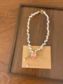 Detailopname van de roze rozen parelketting met delicate kralen en een romantische stijl. - Parel Roos Stijl (XL4386D)