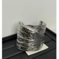 Detailed shot of a bold silver metal wide cuff bracelet with unique textured surface finish. - Asymmetric Cross Textured Silver Style (Z-804)
