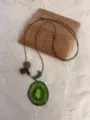 Detailed view of the kiwi fruit slice resin pendant necklace with brown cord and beads. - Kiwi Necklace Style
