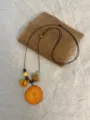 Detail view of long resin fruit slice sweater chain with wooden beads and natural elements. - Light Carrot Style