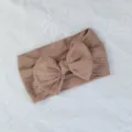 Primer plano de una diadema para bebé de nailon marrón con punto trenzado y lazo - Estilo de Lazo Torcido / Marrón Vintage